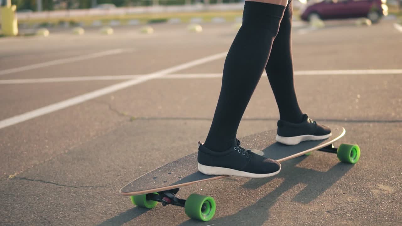 vista de cerca de las piernas de la mujer en zapatillas negras y calcetines largos patinando en la carretera de la ciudad