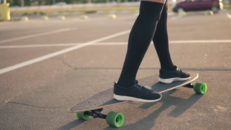 Closeup-View-Of-Woman's-Legs-In-Black-Sneakers-And-Long-Socks-Skateboarding-On-The-Road-In-The-City