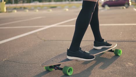 closeup view of woman's legs in black sneakers and long socks skateboarding on the road in the city