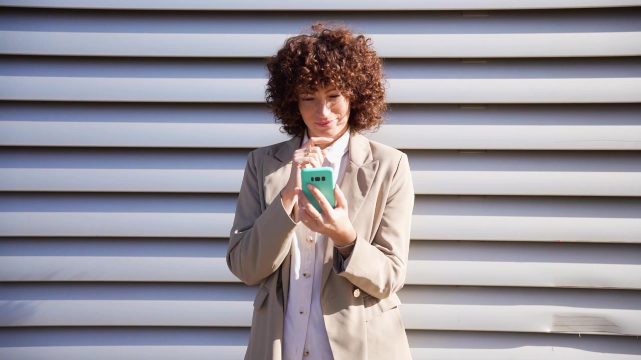Una donna d'affari sicura di sé con i capelli ricci è al telefono, mostrando la sua professionalità.