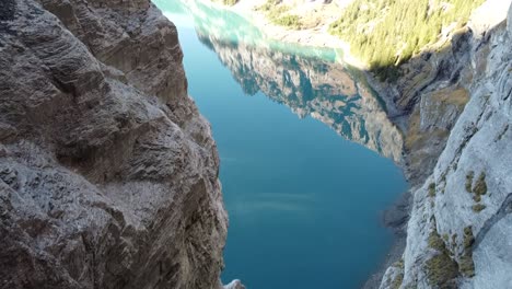 cámara panorámica hacia arriba con vistas a las montañas suizas reflejadas en un lago de montaña azul profundo único, hermoso clima soleado y cielos azules