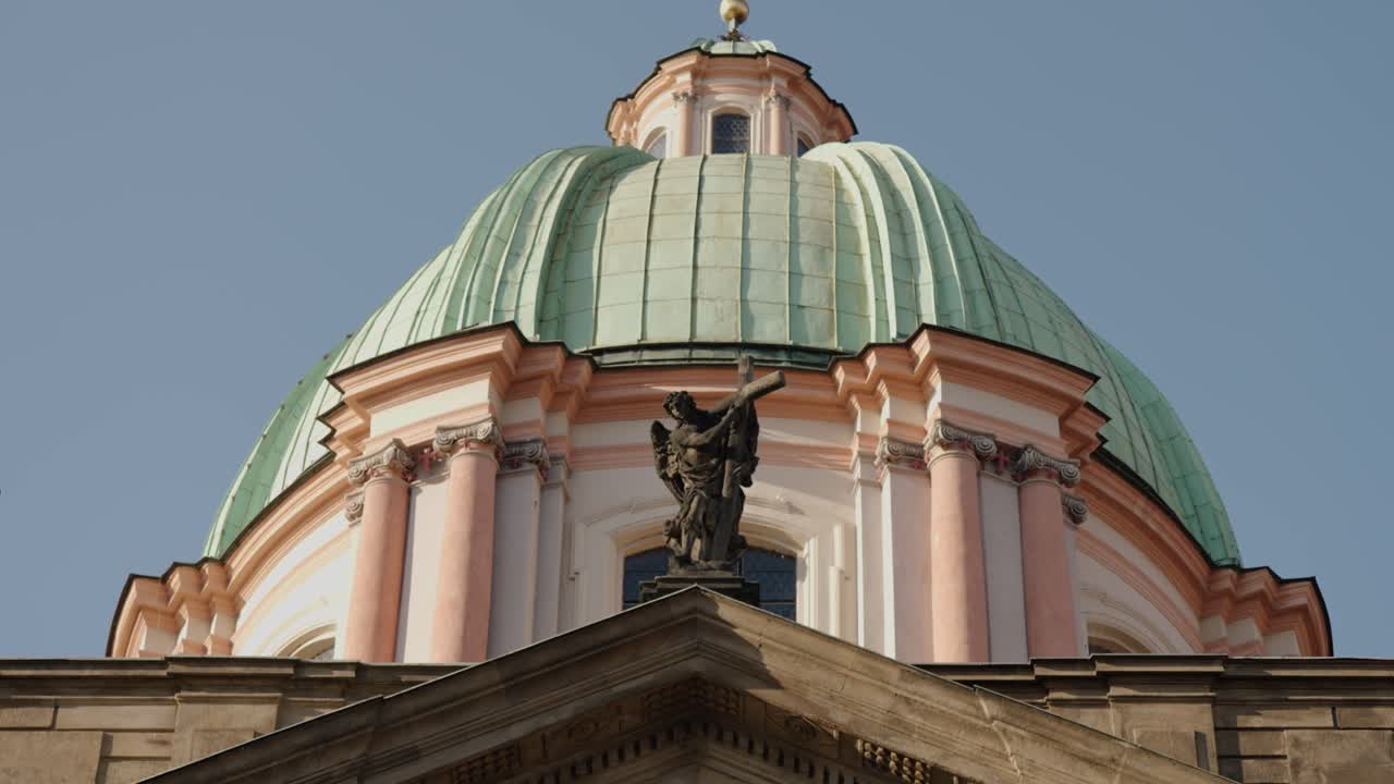 Close-up view of St. Francis of Assisi Church dome with angel statue and cross in Prague