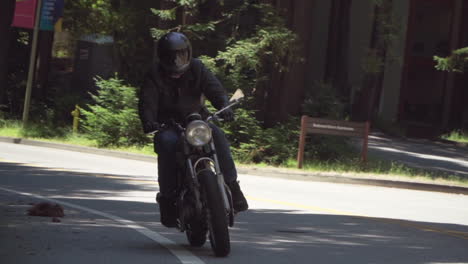 slow motion of motorcyclist with leather jacket riding on a wooded road