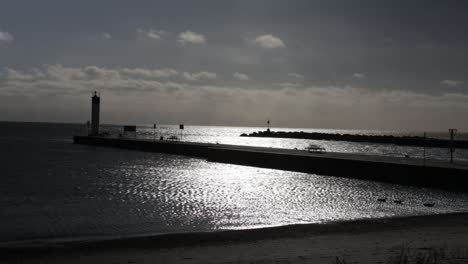 Waves-gently-crash-into-a-beach-alongside-a-pier