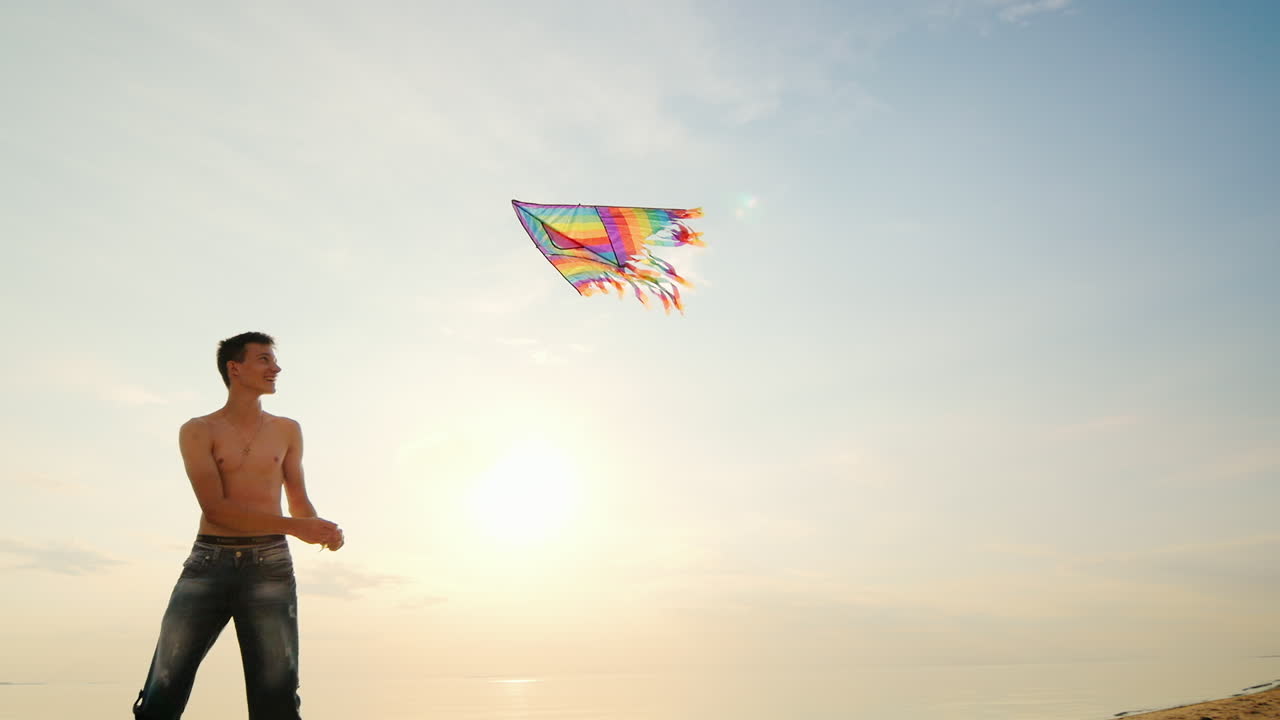 niño adolescente jugando con una cometa contra el fondo de la vista lateral del cielo azul