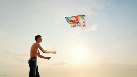 boy teenager playing with a kite against the background of blue sky side view