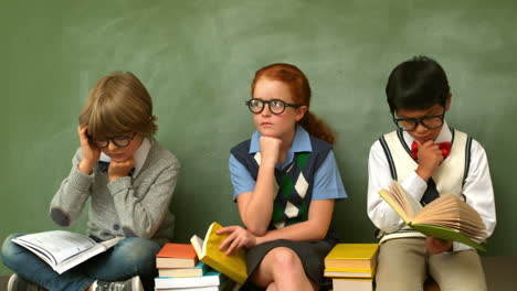 focused pupils sitting in classroom reading books