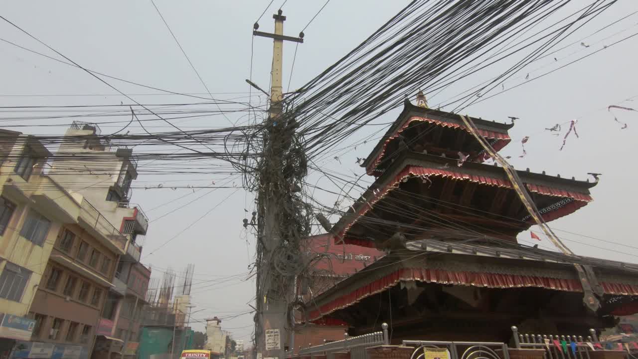 Low Pan shot of messy wires dangling from poles, Nepal Electricity