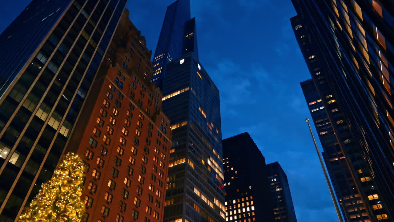 Grattacieli di New York da una prospettiva dal basso di notte. Vista sull'albero di Natale decorato con palle dorate e luci