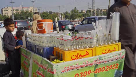 young boy selling lemonade on busy street in pakistan