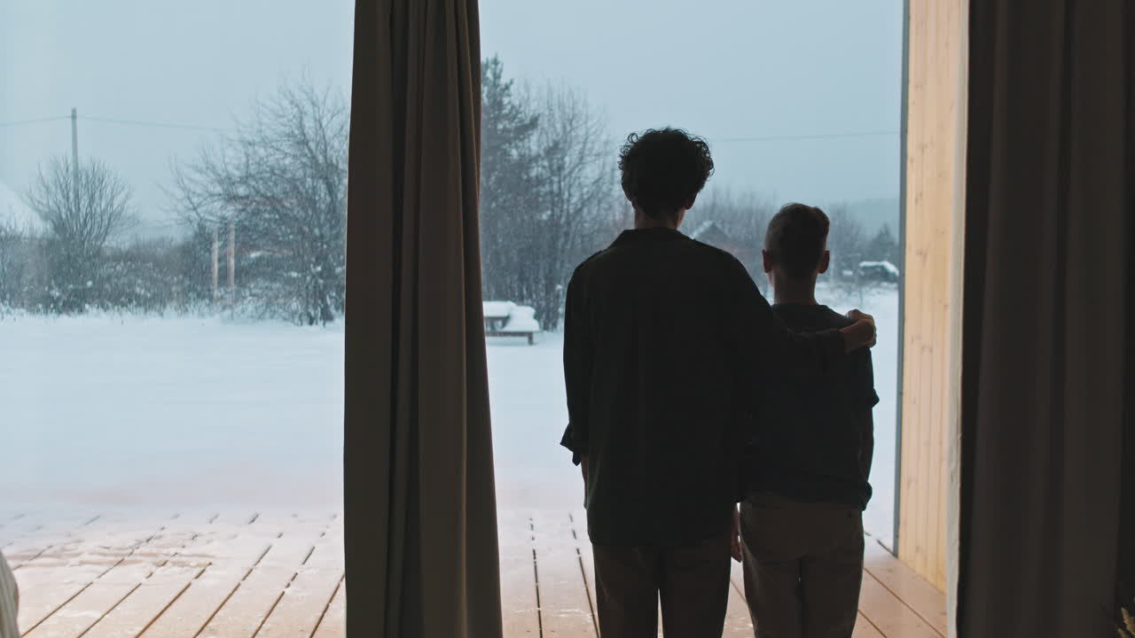 Mom And Son Standing By Panoramic Window In Winter