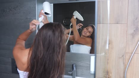 una mujer secándose el cabello en un baño.