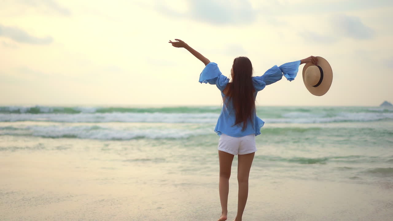 mujer asiática con el pelo largo lleno de alegría al atardecer en la playa