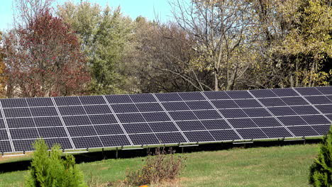 Paneles-Solares-En-El-Césped-Con-árboles-De-Otoño-En-Segundo-Plano.