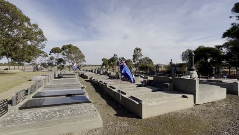 australian flags flying on world war heroes graves in a cemetery, celebrating anzac day.