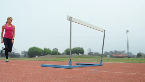 low angle view of female athlete jumping over hurdles on a running track 4k