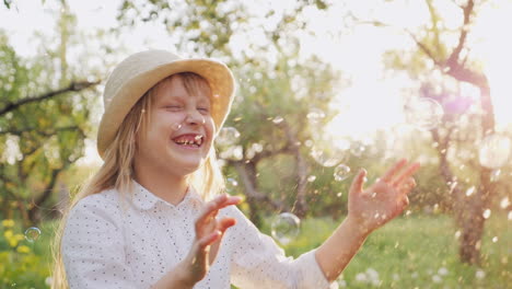 a cheerful girl in a hat carelessly plays with soap bubbles happy spring and good weather slow motio