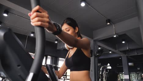 cheerful asian girl smiling while exercising in the gym with headphones on her neck