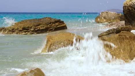 rocks splashed by white waves with blue turquoise sea water background in mediterranean