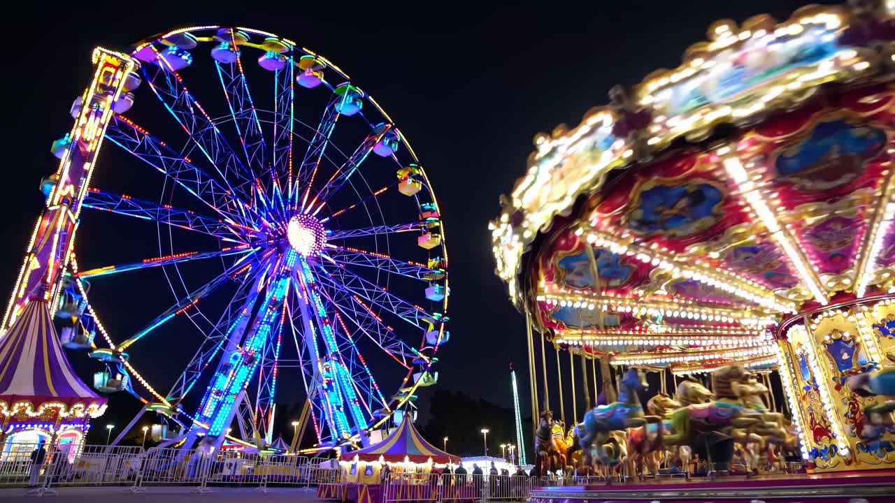 Vibrant video of a carnival at night, showcasing a low-angle view of a brightly lit Ferris wheel