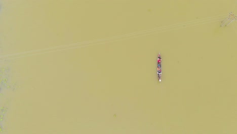 4k aerial top down shot of people in a row boat getting evacuated to land area in majuli river island submerged in the brahmaputra monsoon floods