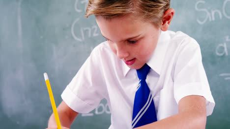 Schoolboy-doing-his-homework-in-classroom