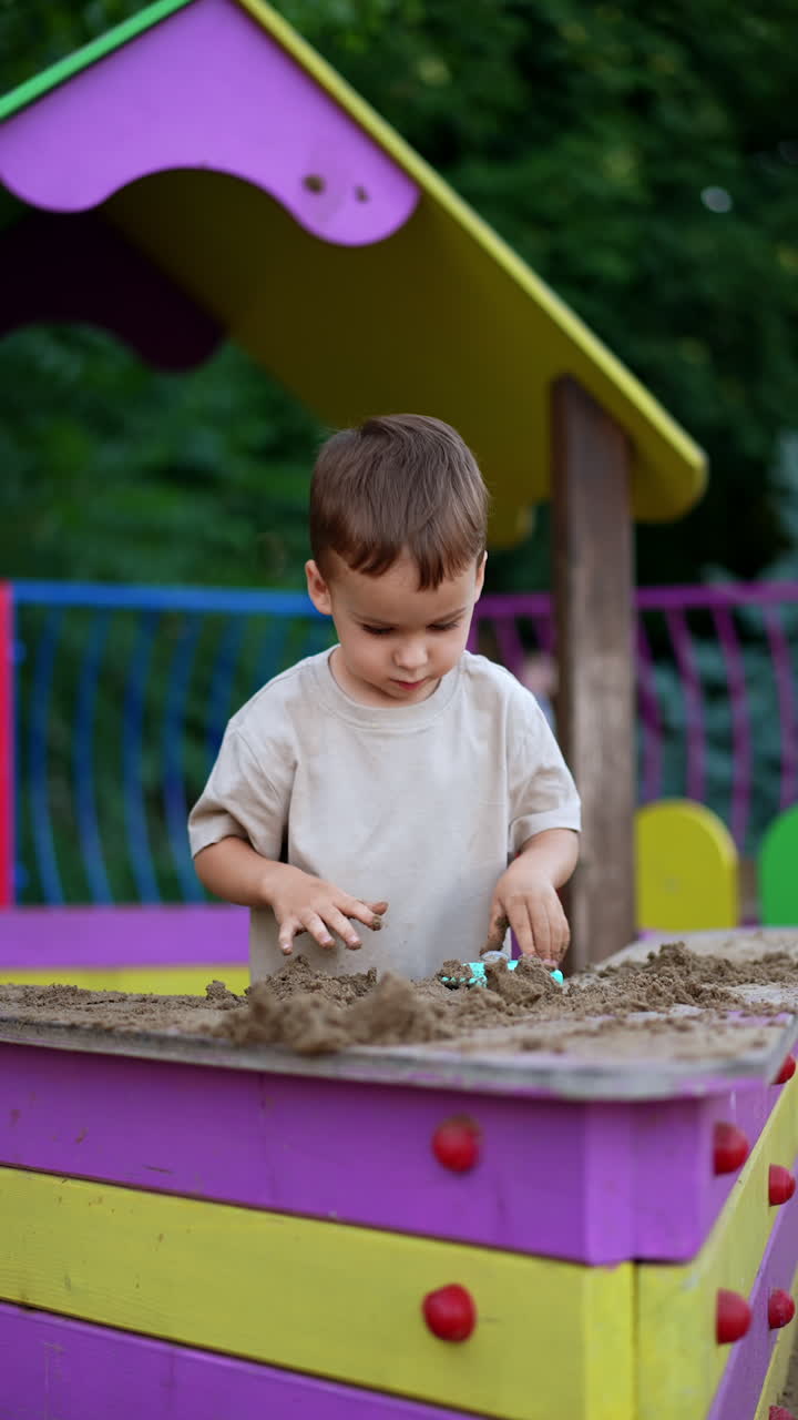 Lovely Caucasian toddler plays with sand in sand box. Kid pushes the ...