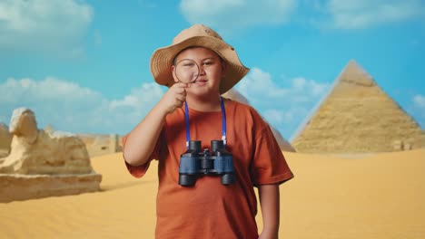 asian boy with a hat and binoculars looking through the magnifying glass examines something while traveling in giza pyramid. boy researcher, travel tourism adventure concept