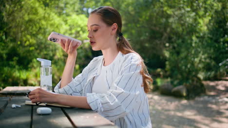 girl recording audio message at forest table close up. woman using voice app