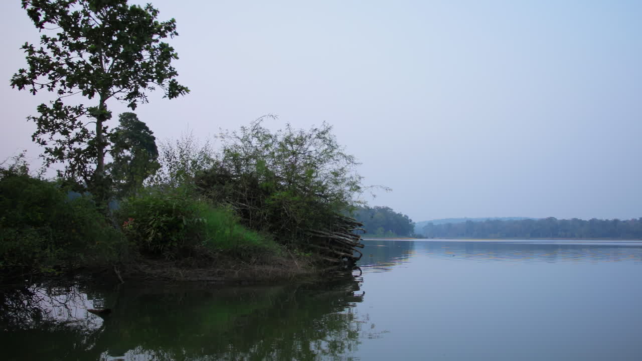 Boat observation slowly passing overgrown wetland mound on Kabini river in Nagarhole national park
