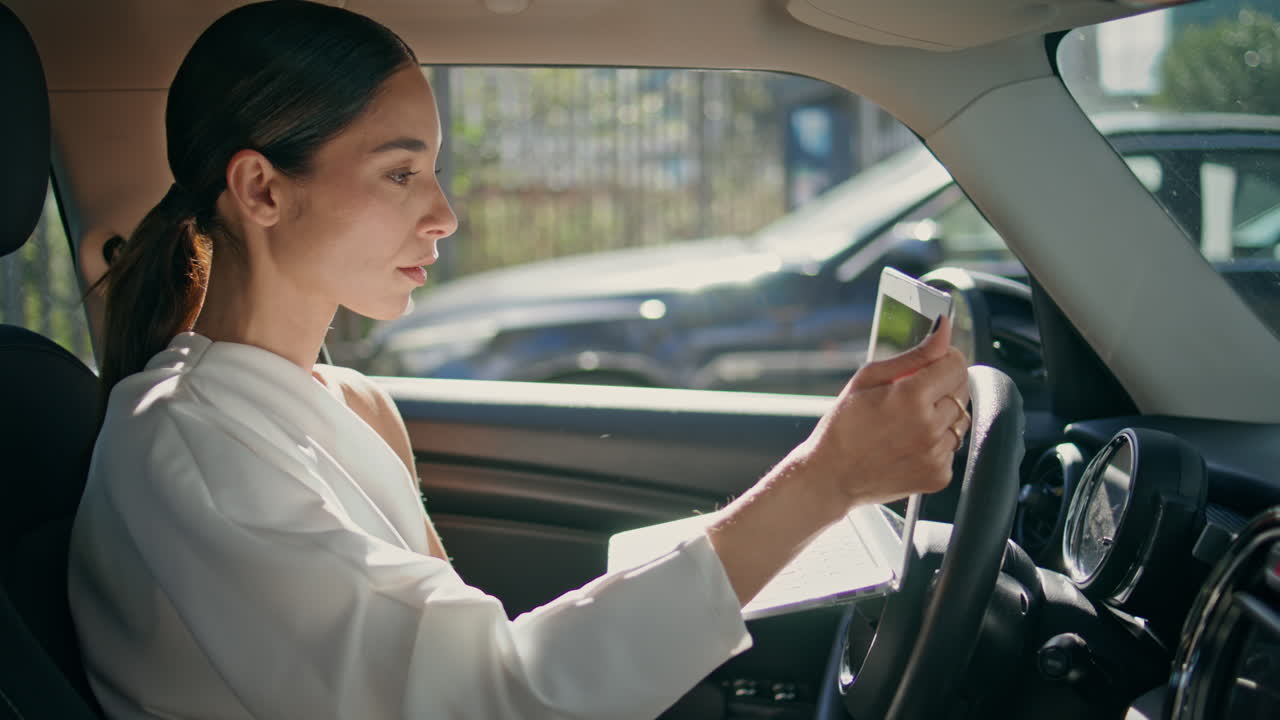 chica freelance trabajando en un portátil sentada en un coche de primer plano. dama mirando la pantalla de la computadora