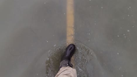 a man walking on a flooded automobile road, water reaching his ankles