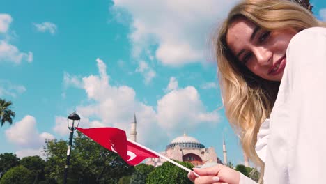 beautiful young girl takes selfie and waves turkish flag in front of an ancient building in lstanbul,turkey,travel concept