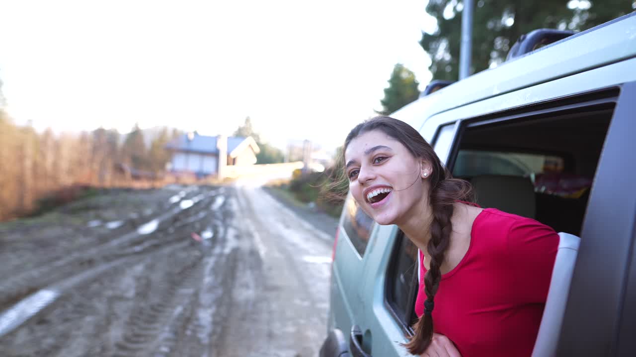mujer feliz mirando por la ventana del coche en un camino de tierra