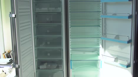 man opening and closing an empty refrigerator