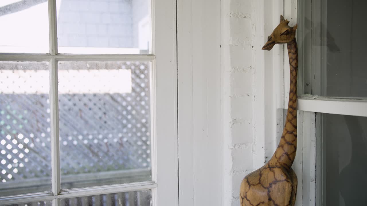Handmade Giraffe Statue leaning against window in sun room