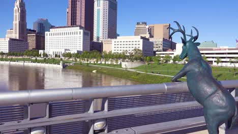 a deer sculpture overlooks columbus ohio from a bridge