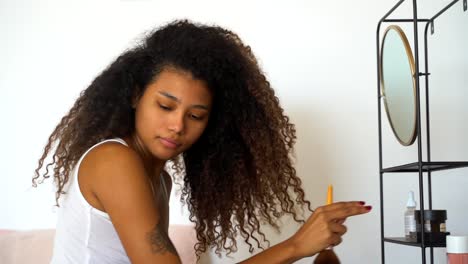 young ethnic woman applying makeup near mirror