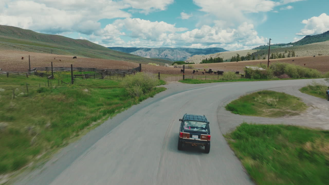 Truck drives down rural road towards cattle farm