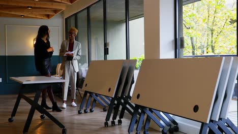 Front-view-of-young-mixed-race-business-colleagues-discussing-over-documents-in-modern-office-4k