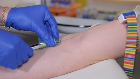 close up of doctor or nurse taking a blood sample from arm vein with a vacutainer. syringe to venipuncture the patient