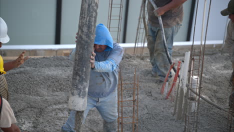 movimiento lento de un grupo de trabajadores de la construcción latinos mexicanos vertiendo mezcla de hormigón húmedo en la cuadrícula de piso de una casa nueva