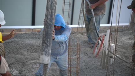 slow motion of a group of mexican latin construction workers pouring wet concrete mix on the flooring grid of a new house