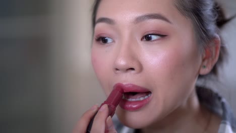 charming woman applying bright lipstick