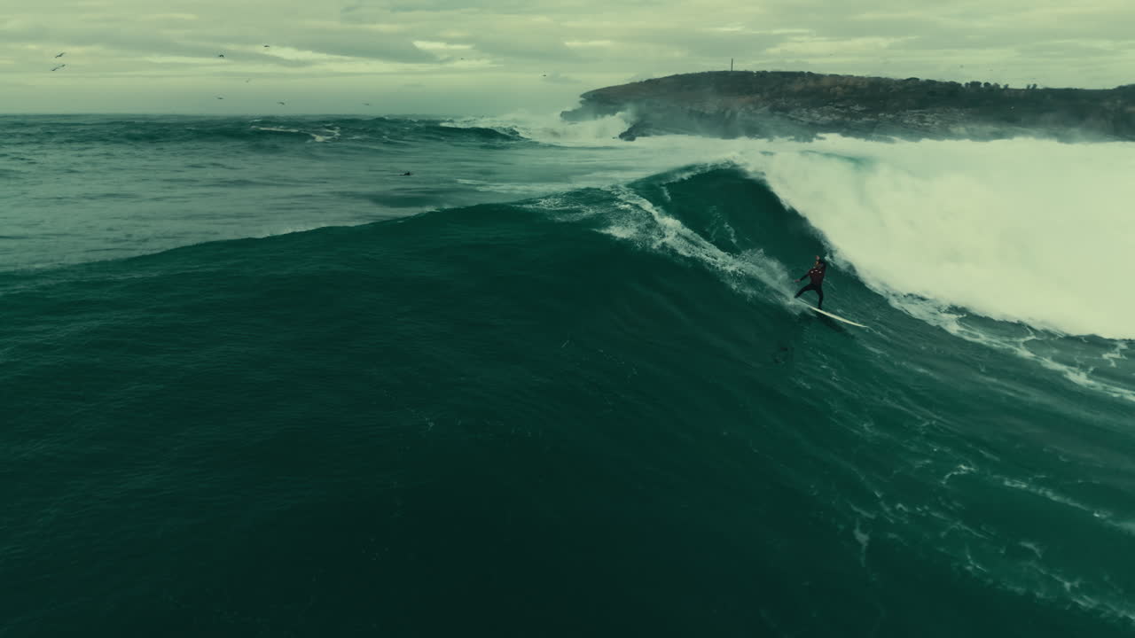 Vista aerea di un surfista che cavalca un'enorme onda oceanica
