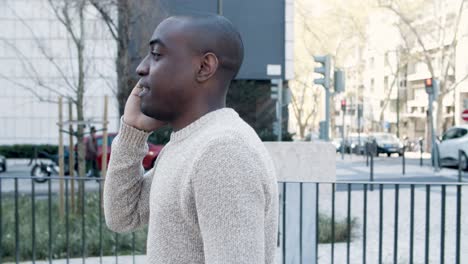 Smiling-man-talking-on-phone-while-walking-on-street