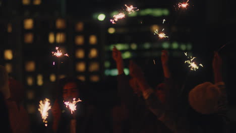 Fröhliche-Freunde-Halten-Wunderkerzen-In-Der-Hand-Und-Feiern-Silvester-Auf-Dem-Dach-Bei-Sonnenuntergang-Und-Haben-Spaß-Daran,-Die-Feiertagsfeier-Zu-Genießen