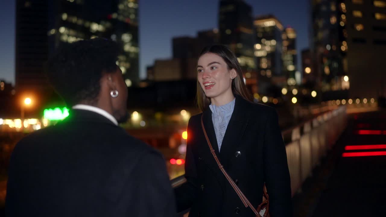 Two people having a conversation in the city at night