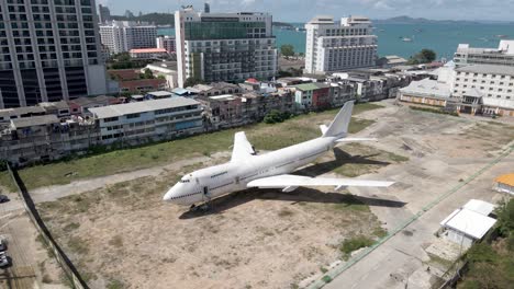 aerial pullback from white old aircraft parked in pattaya city centre, runaway 88 street project, thailand