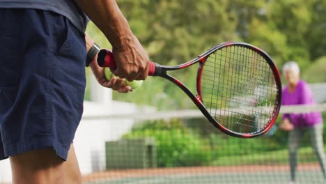 video of hands of biracial senior man holding racket and starting match on tennis court
